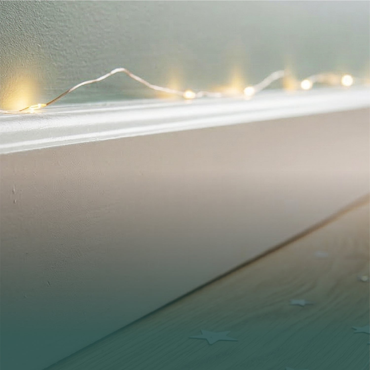Warm fairy lights on white baseboard with star confetti on wood floor